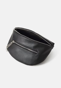 Borsa in pelle nera con due scomparti con zip, superficie testurizzata e un'accennata catena argentata sul davanti per un tocco di stile.