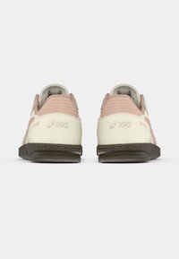 Vyriški ASICS sportbačiai kreminės ir šviesiai rožinės spalvos. Odinis ir tekstilinis viršus su reljefiniais akcentais, gumine pado danga ir prekės ženklo ženklinimu ant kulno.