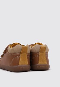 Chaussures en cuir marron avec un talon en daim tan, dotées d'une sangle à boucle et d'un col rembourré pour le confort. Semelle en caoutchouc texturée.