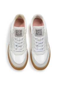 Sneakers bianchi in pelle con finitura lucida, suola in gomma color cuoio a contrasto, punta rotonda, lacci e dettaglio del logo sulla linguetta. Texture liscia.