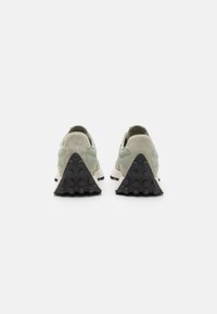 Sneakers feature a light gray suede upper with a textured mint green mesh panel. Black rubber outsole has a triangular shape with circular grips.