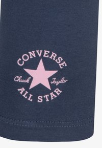 T-shirt Converse in cotone blu navy con un logo circolare rosa caratterizzato da una stella e dal testo "Converse Chuck Taylor All Star."