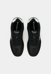 O pereche de sneakers negri Champion cu detalii albe ale logo-ului, șireturi negre și talpă maro, prezentată dintr-o perspectivă de sus pe un fundal alb.