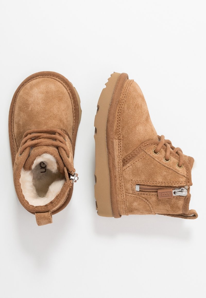 Bottes pour enfants en daim marron avec doublure en fourrure, lacets et fermeture éclair latérale, présentées vues de dessus et de côté sur fond blanc.