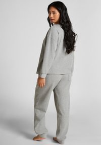 Grijze loungewear set met een getextureerde, lange mouw top en bijpassende broek. Beide hebben een relaxed fit met geribbelde accenten en geen zichtbare sluitingen.