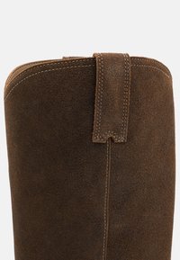 Ruskean mokkanahka ankle boot, jossa on sileä pinta, pyöreä muoto ja takana oleva silmukkavetoketju, jossa on kontrastiväriset ommeltyöt.