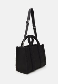 Fekete vászontáska plüss textúrájú díszítéssel, két felső fogantyúval és állítható vállpánttal, tartós anyagból készült.