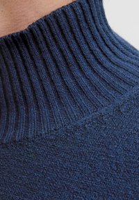 Suéter de cuello alto de color azul oscuro, tejido con un diseño de canalé en el cuello. La tela presenta un patrón texturizado y está hecha de un material suave y cálido.