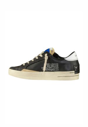 Sneaker nera e grigia con una tomaia testurizzata, lacci crema e suola crema. Presenta un logo stampato sul lato e un accento blu sulla linguetta.