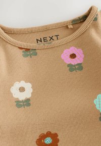 Top in tessuto beige a coste con motivi floreali colorati in rosa, bianco, marrone e turchese. Collo rotondo con etichetta del marchio.