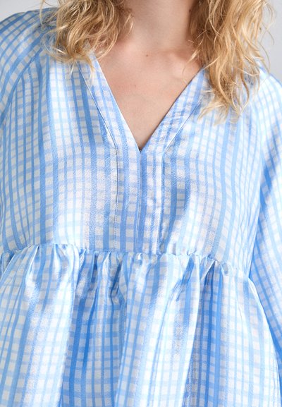Robe à carreaux bleu clair avec un col en V, des manches bouffantes et une taille froncée. Fabriquée à partir d'un tissu doux et texturé avec des accents de motif à carreaux.
