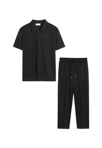 Chemise noire à manches courtes et col, avec un pantalon noir à taille élastique et cordon de serrage, ensemble décontracté assorti.
