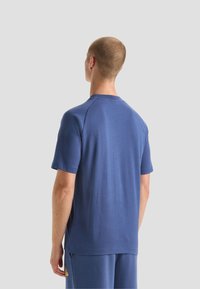 T-shirt blu navy a maniche corte in tessuto morbido, con scollo rotondo e vestibilità rilassata. Il retro presenta una texture liscia con sottili dettagli di cucitura.