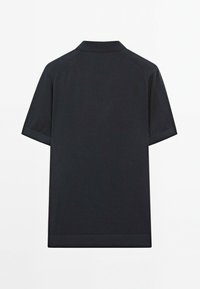 Černé tričko s krátkým rukávem, které má klasický límec, hladký materiál a rovný lem. Zadní strana zobrazuje jednoduchý, minimalistický design.