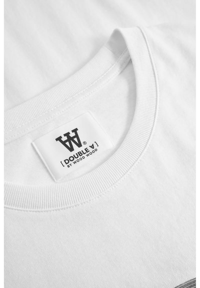 Tricou alb din bumbac cu guler rotund, guler ribbat și o etichetă pe care scrie "DOUBLE V BY WOOD WOOD" cu text negru.