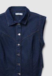 Camicetta senza maniche in denim blu scuro con colletto, chiusura frontale con bottoni e dettagli di cucitura arancione a contrasto.