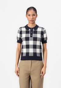 Kratkām piedurknēm polo krekls ar tumši zilu un baltu ķekaru rakstu, ar ribotu apkakli, trīs pogu slēgšanu un teksturētu audumu.
