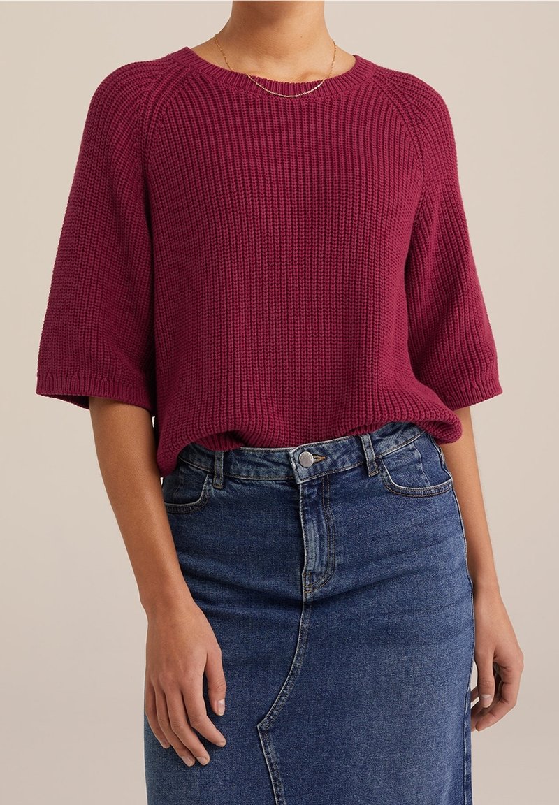 Vinröd stickad tröja med korta ärmar och ribbat mönster, ihopparad med en jeanskjol i blyertsstil med framseams och knappstängning.