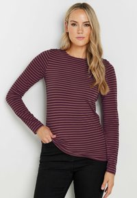 Pitkähihaisen viininpunaisen raidallisen paidan pyöreä kaula-aukko ja kaareva helma. Paidassa on vaaleanruskeita vaakaraitoja ja sileä kangas.