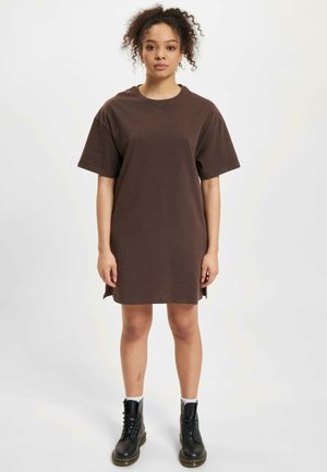 Brown cotton t-shirt dress with short sleeves, round neckline, side slits, and a loose fit, paired with black lace-up boots.