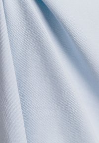 Lichtblauwe geweven stof met zichtbare textuurpatronen en plooien die zachte schaduwen en diepte creëren.