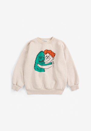 Beżowa bluza z ilustracją rudowłosej osoby przytulającej uśmiechnięte zielone monstrum z przodu.
