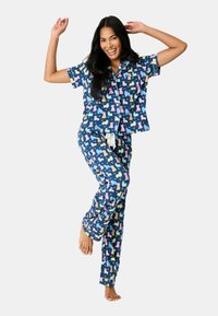 Blå pyjamasset med ett lekfullt hundmönster i rosa, gult och orange. Kortärmad topp med krage och byxor med dragsko.