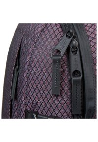 Batoh s texturovanou látkou v tmavě fialovém a černém vzoru diamantů, vybavený černými zipy a odpovídajícími táhly.