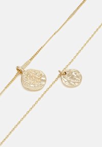 Gold pendant necklace with two circular charms; one textured with a floral design, the other smooth. Features fine chain links.