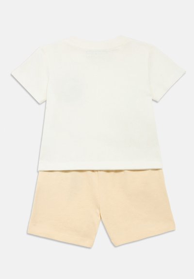 Λευκό βαμβακερό μπλουζάκι με κοντά μανίκια σε συνδυασμό με υπόλευκο κίτρινο βαμβακερό σορτς. Απλός σχεδιασμός, απαλή υφή και χωρίς ορατά σχέδια.