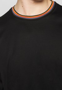 Black t-shirt with a ribbed collar featuring a multicolored striped pattern in red, orange, and blue. Soft fabric texture, casual design.