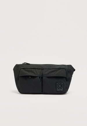 Zwarte gewatteerde stoffen etui met twee voorvakken en een ritssluiting aan de bovenzijde. Voorzien van het Calvin Klein-logo in een vierkant rechtsonder.