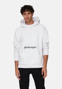 Sudadera blanca de algodón mezcla con corte oversize, que presenta un bolsillo frontal y un estampado negro de "Michelangelo". Puños y dobladillo acanalados.