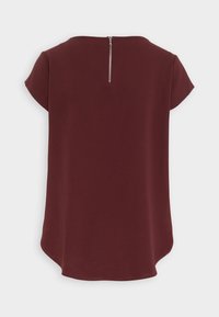 Top borgogna con scollatura tonda, maniche corte e zip sul retro. Realizzato in tessuto morbido con orlo curvo per una vestibilità rilassata.