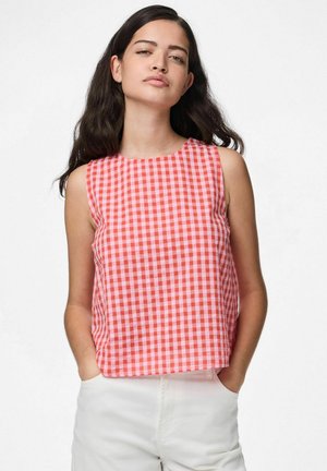 Blusa sin mangas de cuadros rojos y rosas con escote redondo, textura suave y corte recto, combinada con pantalones de color claro.