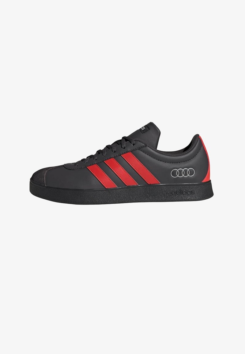 Baskets synthétiques noires avec des bandes rouges et un logo Audi gris, dotées d'une semelle en caoutchouc et d'une conception à bout arrondi.
