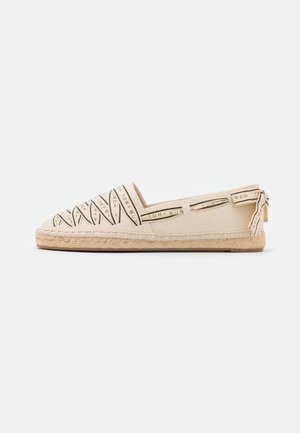 Espadrille en toile beige avec motif tissé, semelle en caoutchouc et bordure en corde claire. Présente un logo sur la tige et à l’arrière.