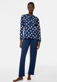 Ensemble de pyjama marine comprenant un haut à manches longues avec des accents en motifs blancs et roses, et un pantalon droit assorti en tissu doux.