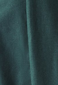 Teal kangas, jossa on teksturoitu pinta, joka näyttää hienovaraisen kudontamallin ja pehmeän roikan. Ei havaittavissa olevia kuvioita tai varusteita.