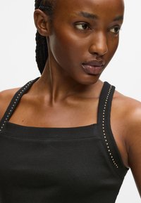 Must mustriba top must, millel kuldsete narmastega õlgadel, ruudukujuline kaelus ja kleitav disain, mis loob stiilse silueti.