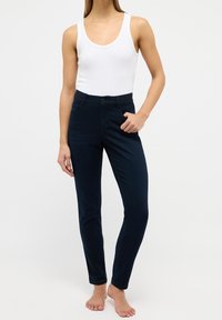 Tmavě modré džíny s úzkým střihem z bavlněné směsi, s pasem ve střední výšce, předními kapsami a jemnými ševními detaily.