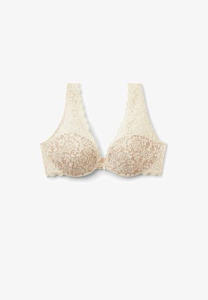 Soutien-gorge en dentelle couleur beige clair avec des bords festonnés et des motifs floraux. Présente des bonnets moulés et une fermeture avant simple. Texture lisse.