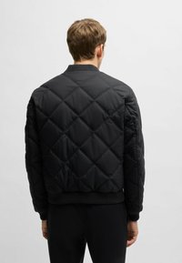 Black quilted bomber jacket with a ribbed collar and cuffs, featuring a diamond pattern and a cropped silhouette.