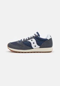 Navy sneaker featuring a mix of suede and nylon, white accents, round perforations, and a gum rubber sole. Classic running shoe design.