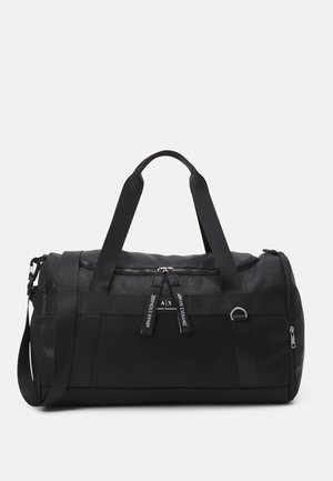 Sac de sport noir en cuir texturé avec doubles poignées et une bandoulière amovible. Il dispose d'une fermeture éclair et d'accents de logo visibles.