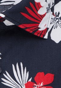 Korte mouwen overhemd met een marineblauwe achtergrond, voorzien van grote witte en rode bloemenpatronen, een spitse kraag en knoopsluiting.