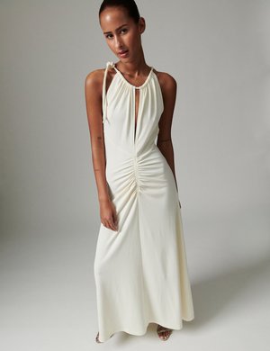 Robe maxi couleur crème avec un col licou, un détail en trou de serrure et un devant froncé. Confectionnée dans un tissu doux à la texture lisse.