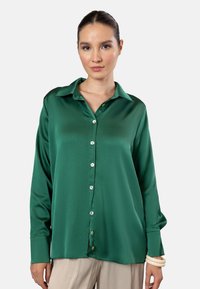 Green satin blouse with a collar, long sleeves, and buttoned front. Features a smooth texture and a slightly loose fit.