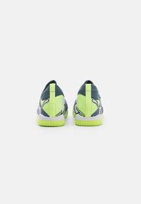 Scarpe sportive con una tomaia in rete, caratterizzate da una combinazione di colori verde e blu navy, superficie texturizzata e suola a contrasto con un design a pattern.