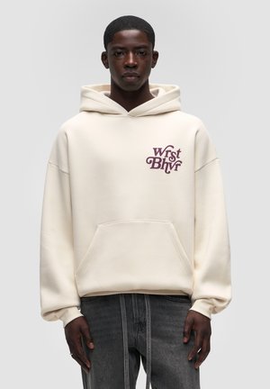 Felpa crema con tasca frontale, vestibilità ampia, cappuccio grande e logo ricamato bordeaux sul petto. Tessuto a trama, design minimale.